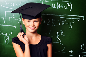 Young girl in graduation cap in front of chalkboard